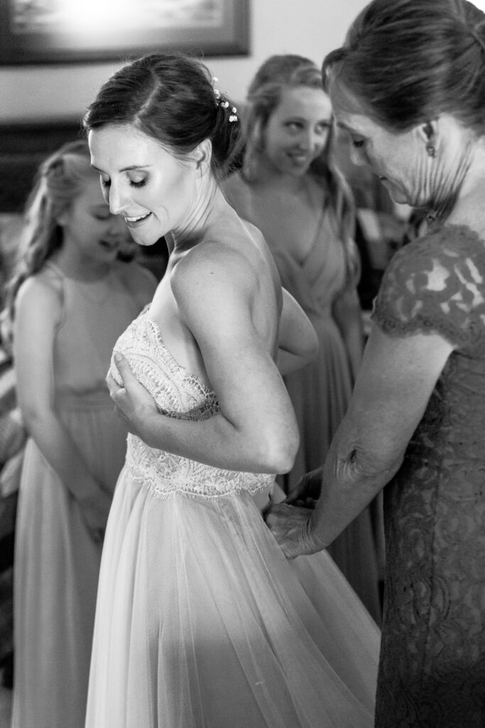 The brides mother buttons her wedding dress