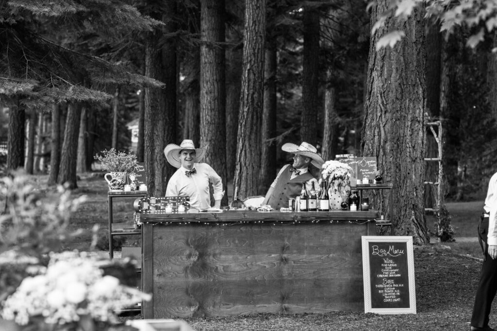 Bar tenders in cowboy hats and sombreros having fun serving drinks at this lake wedding