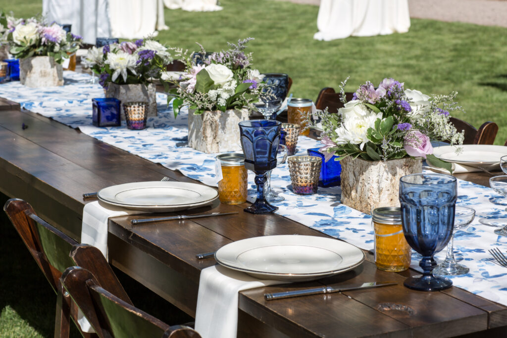 Wedding Reception tables beautifully styled.  Walnut wood table with blue and white floral runner, blue depression glass and traditional southern blue and white patterned dishes