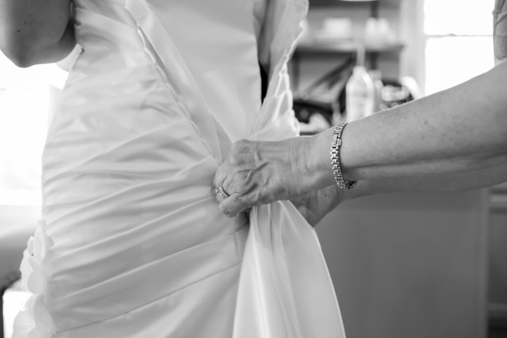 the brides mother buttons her wedding gown