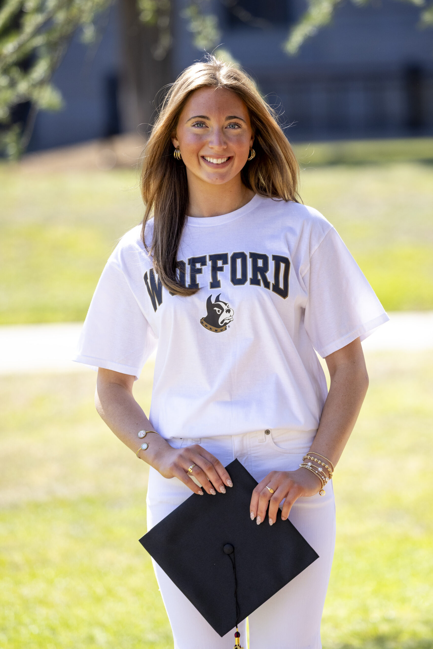 Senior portrait of a Cardinal Newman graduate at the University of South Carolina Horseshoe wearing a Wofford College shirt and holding her graduation cap