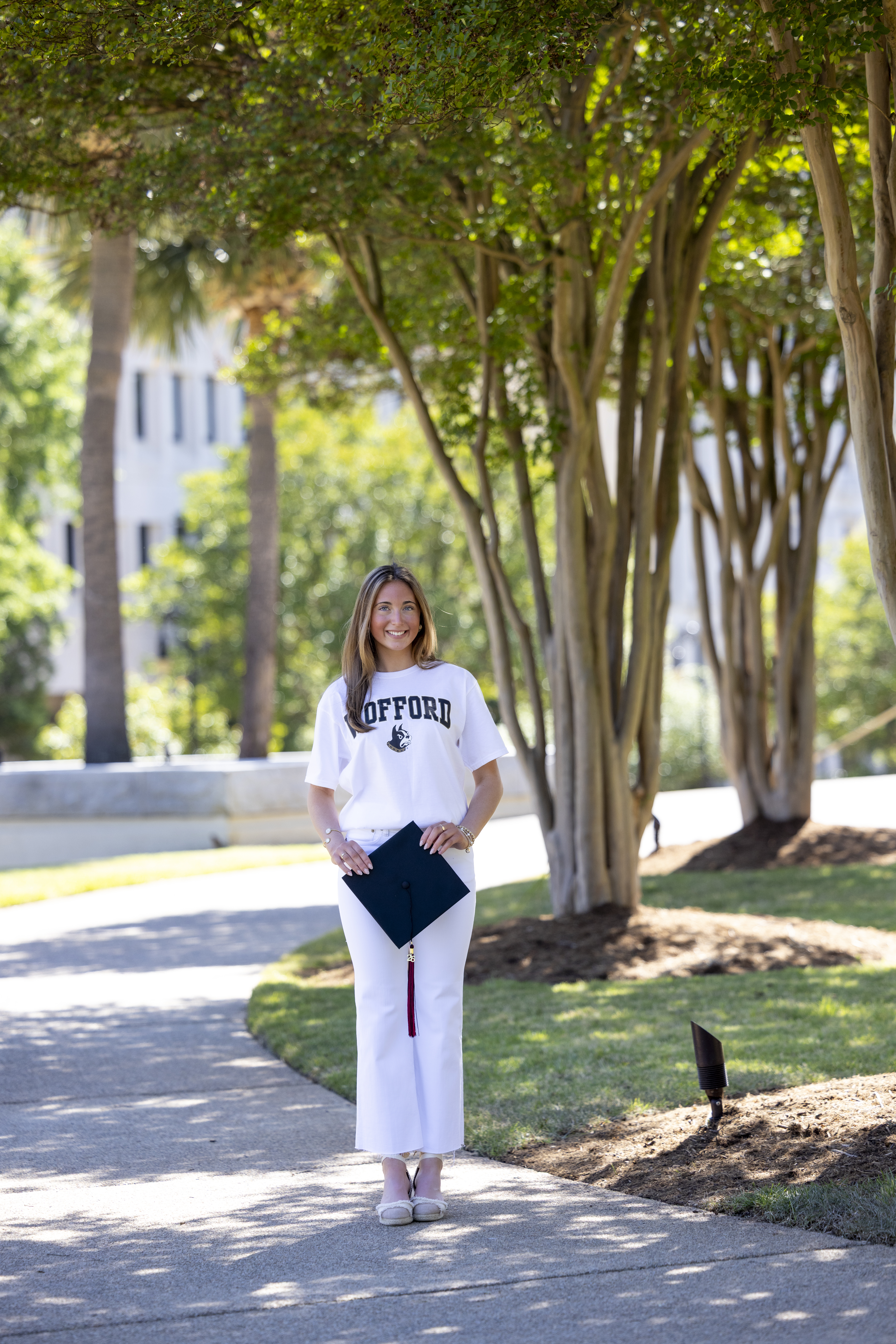 Senior graduation portrait at the USC Horseshoe featuring a Wofford College shirt, graduation cap in hand, and class Columbia, South Carolina campus architecture