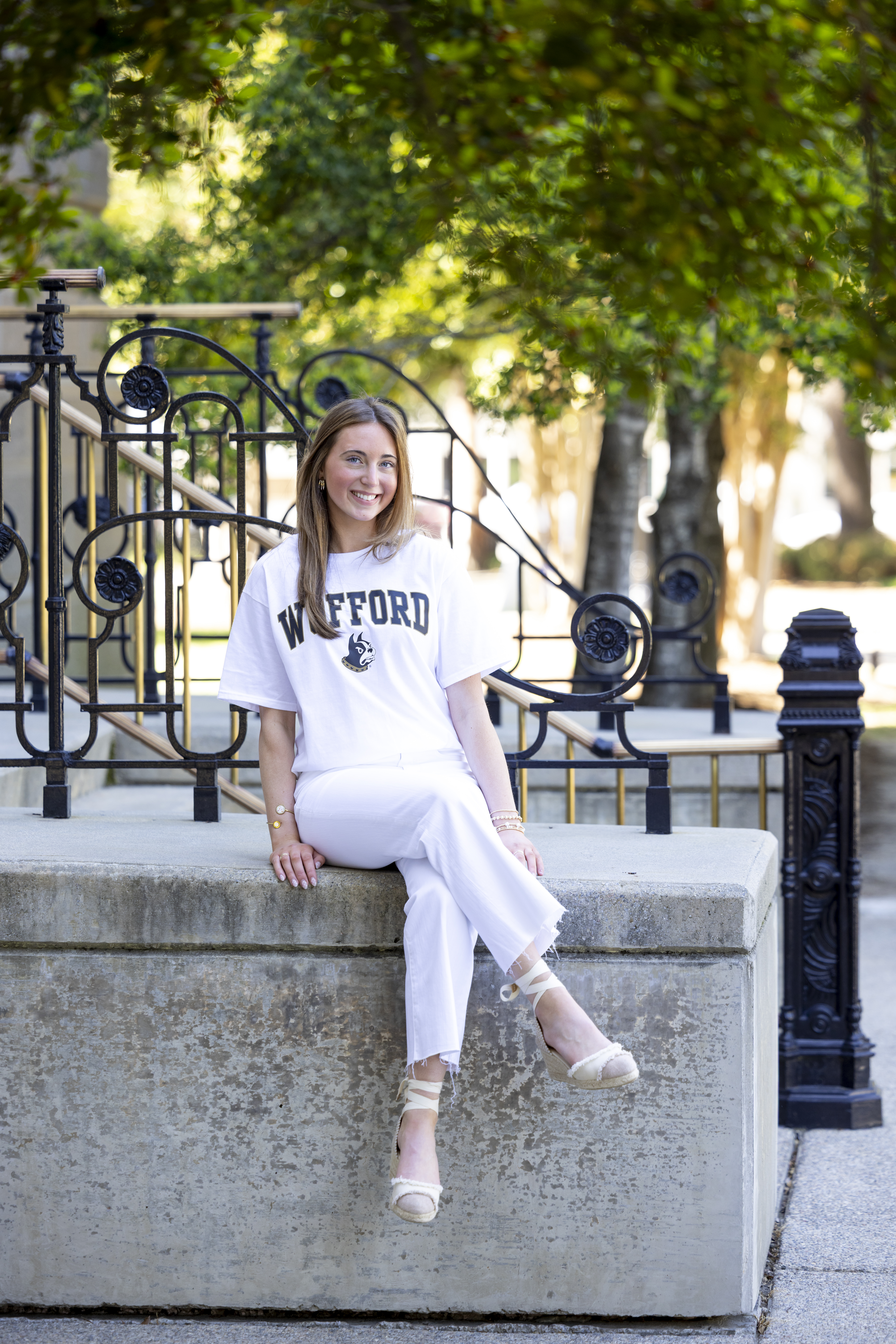 Casual senior portrait of a Cardinal Newman senior smiling at the University of South Carolina Horseshoe while wearing a Wofford College shirt